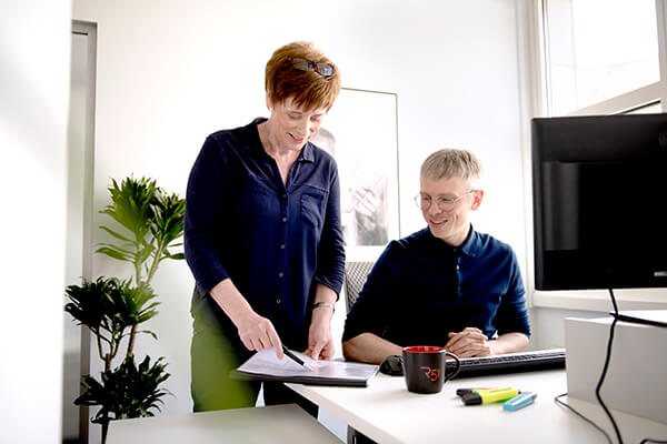 Zwei Personen mit einer Arbeitsmappe und einem Stift