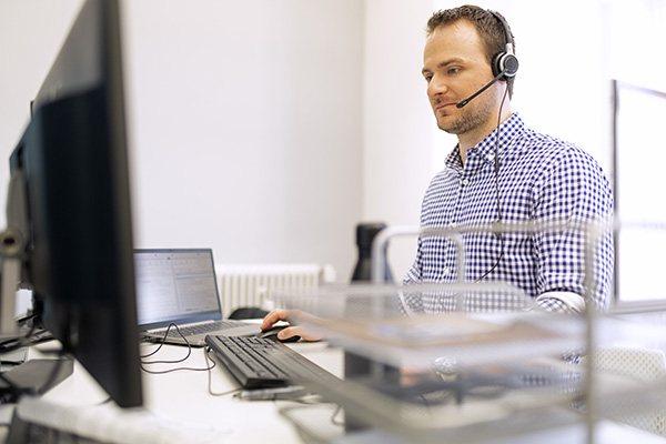 Ein Mann am Schreibtisch und mit einem Headset auf