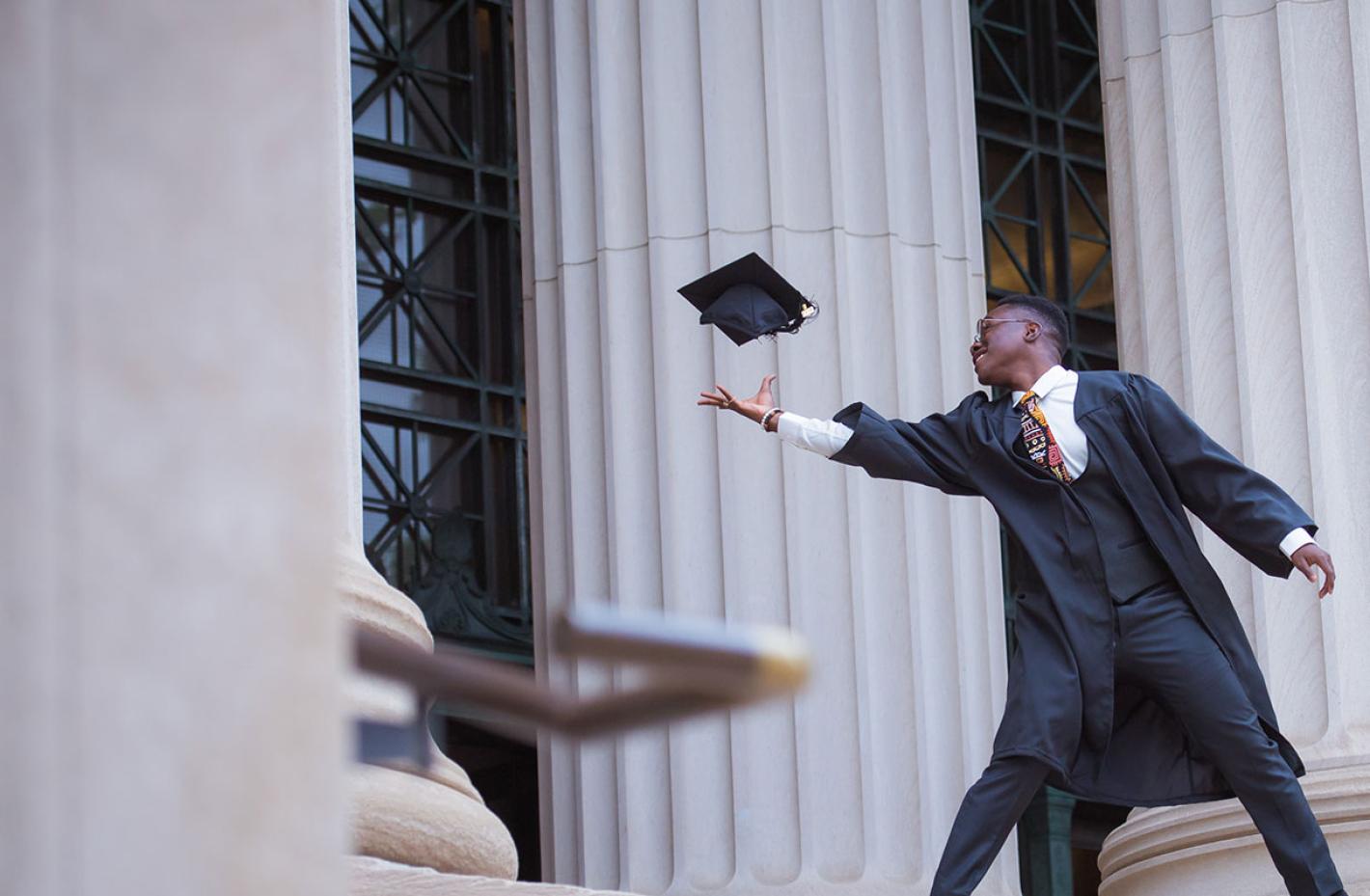 Student tossing graduation cap in the air. 