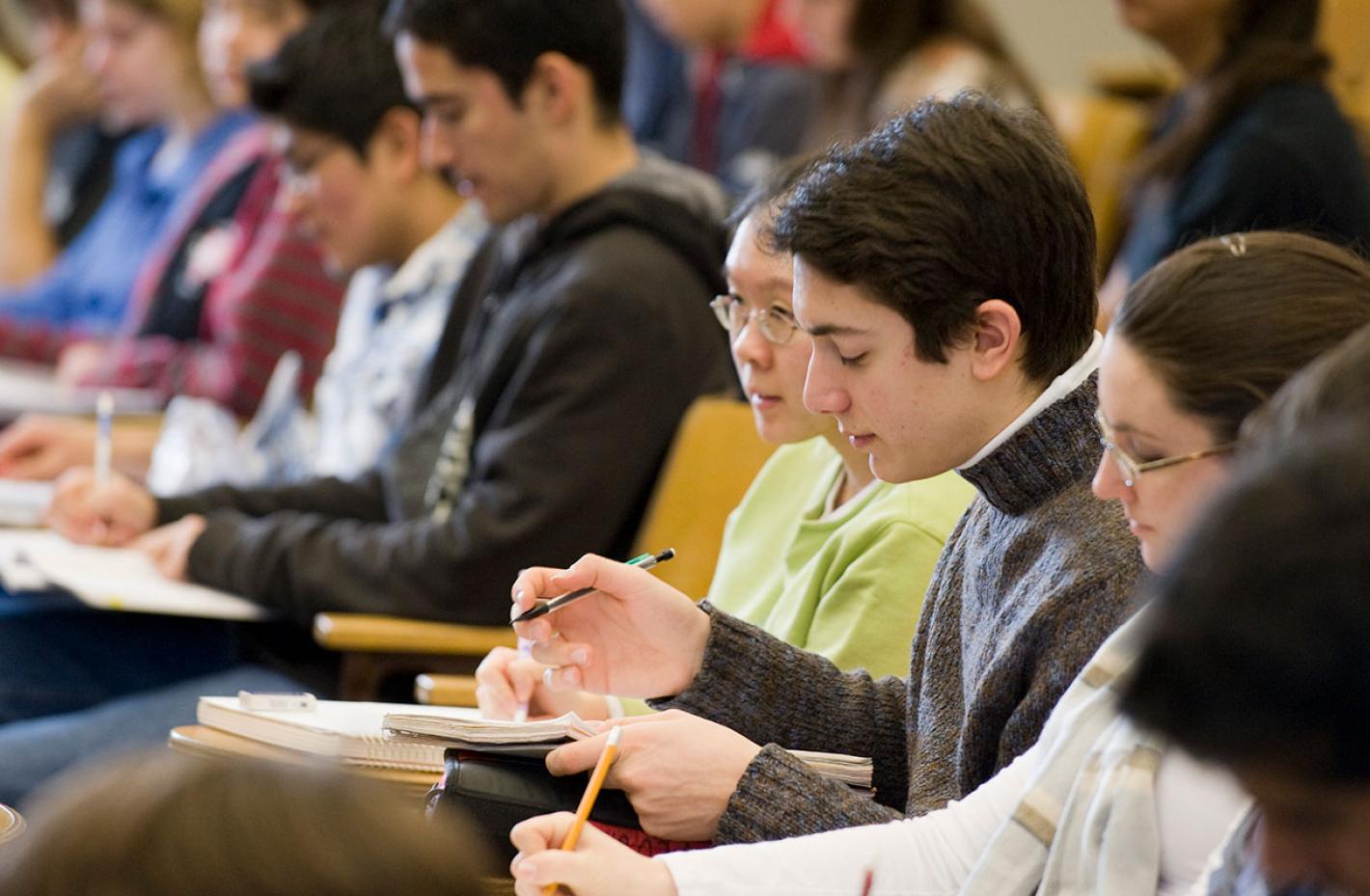 Students taking notes in lecture hall. 