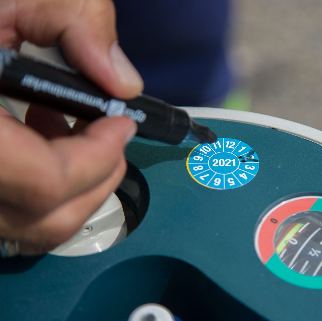 A person marking a parking disc to set the arrival time with a marker pen.