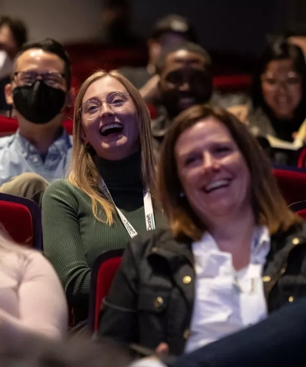 Attendees sitting in the venue, laughing.