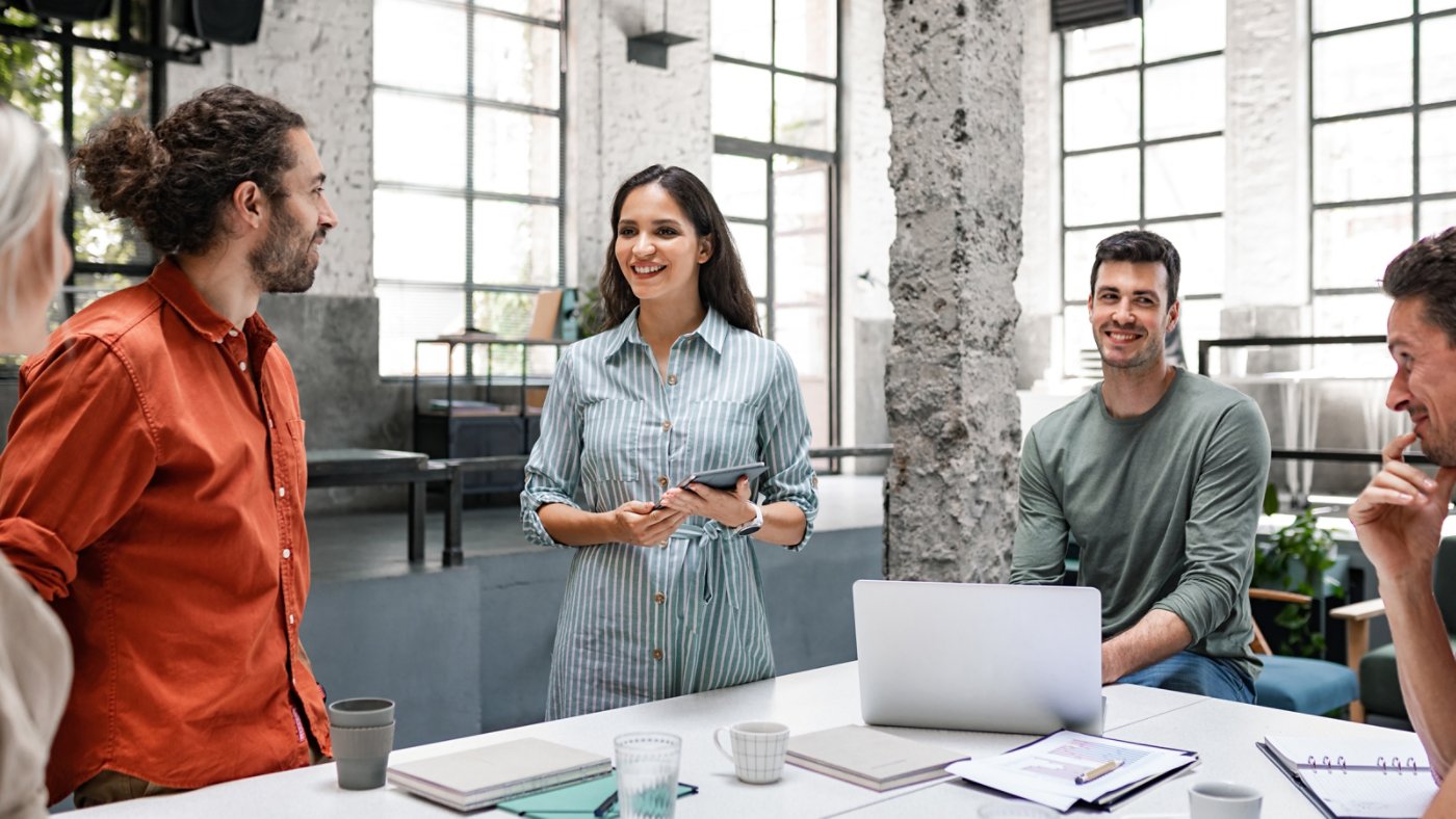 Group of successful businesspeople cooperating by participating in a casual meeting around a standing desk.