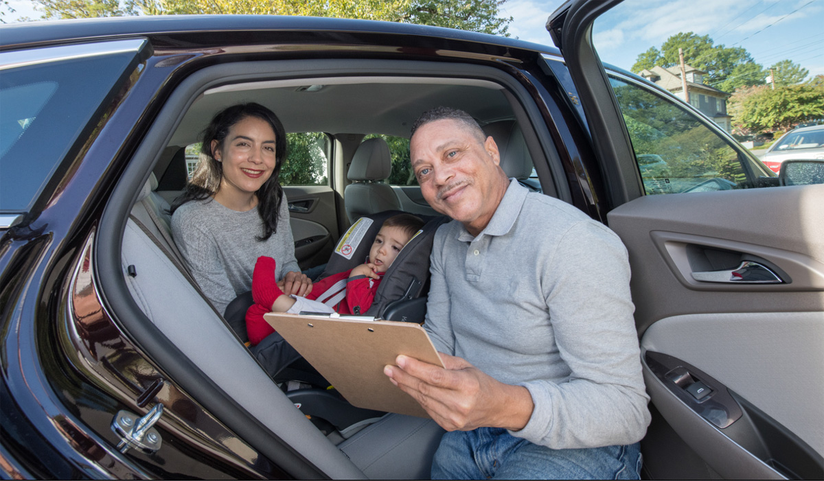 two adult and child in car seat