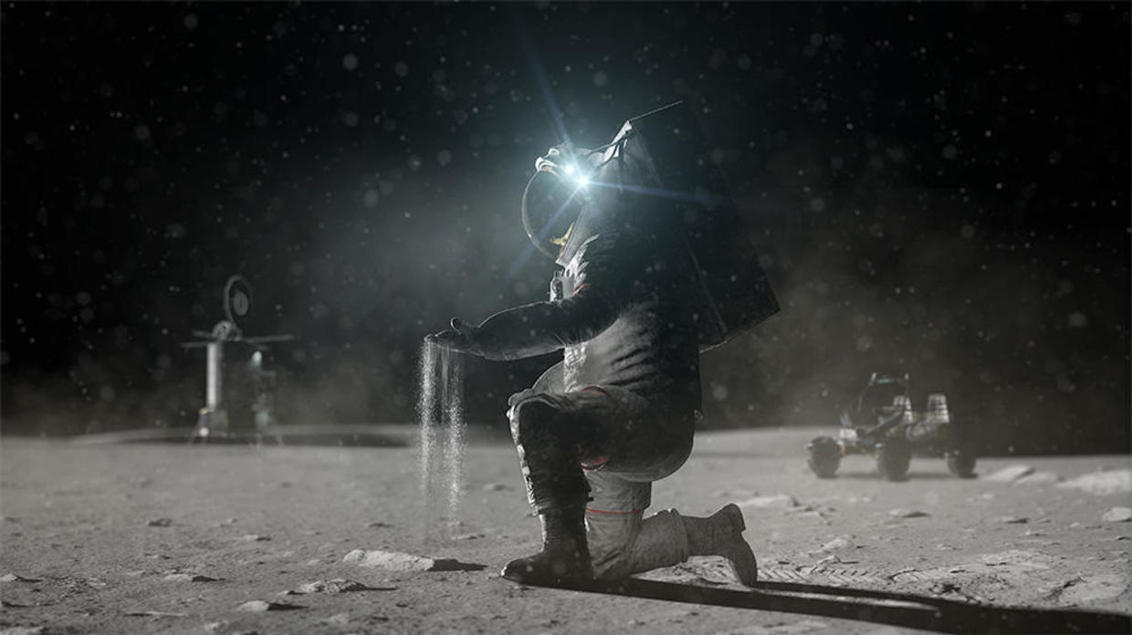 In the foreground is a figure kneeling on a light grey surface, examining or holding something that is sifting through their gloved left hand. The person is wearing a spacesuit and a big, boxy backpack. A reflective visor that catches and reflects bright light, possibly from the Sun, draws the viewers eye. The background is black. In the distance, mechanical equipment or structures are visible, including a small and simple vehicle.