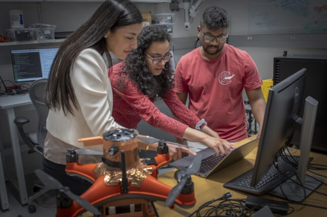 three people looking at a computer