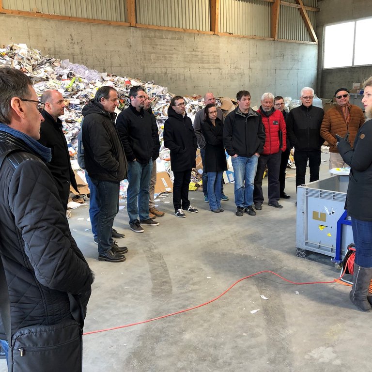 Viele Personen stehen im Kreis und hören Workshop-Leiter zu