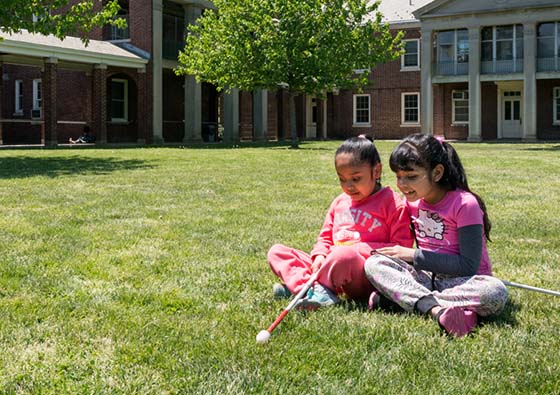 Two friends sitting in the grass at school.