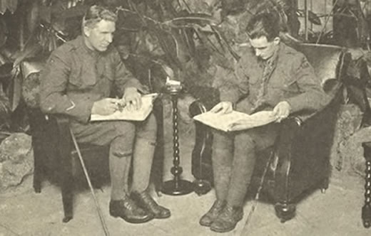 Two white soldiers in World War I uniforms sit in armchairs reading braille text on their laps. Their canes are by their sides.