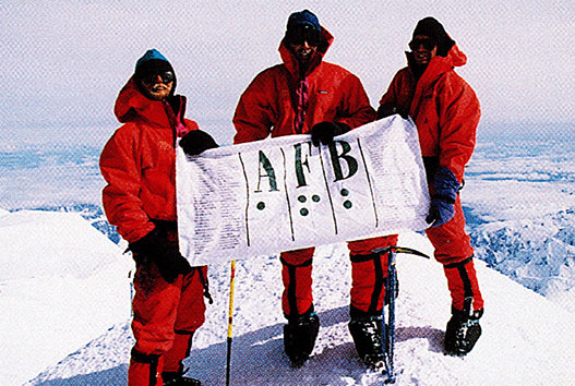 Erik Weihenmayer with three of the other climbers on his team, at the summit of Mt. McKinley, June 27, 1995. They hold the AFB flag, which includes the braille code for the letters A, F, and B.