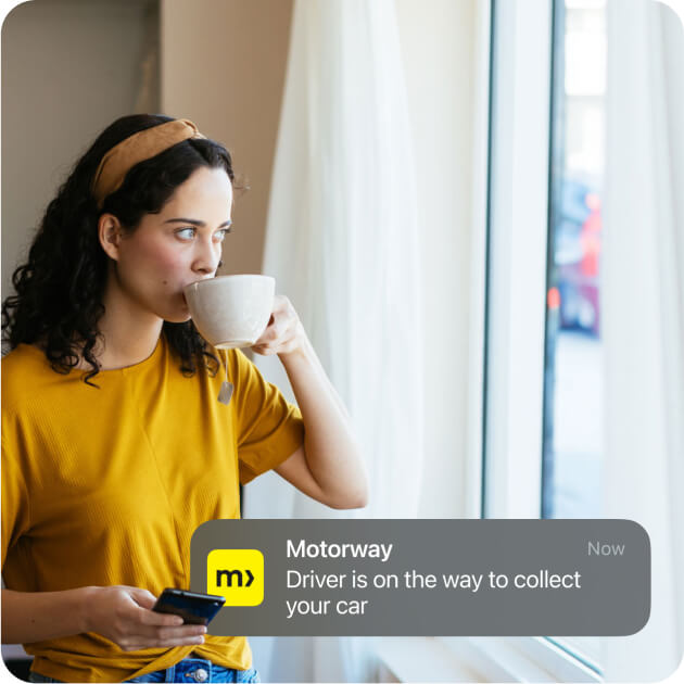 Woman at home drinking tea, holding mobile