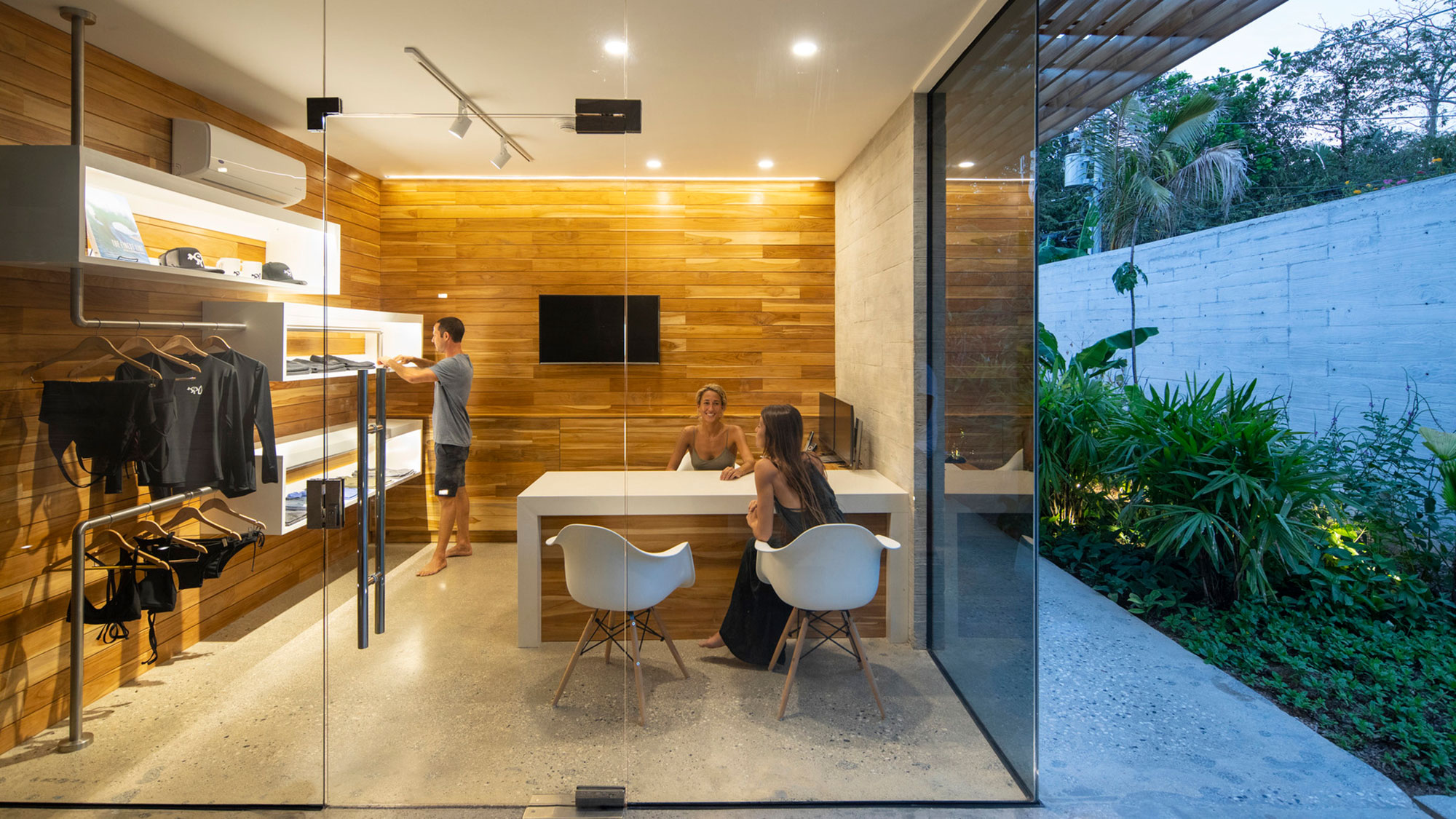 A group of people sitting at a table in a room with plants.