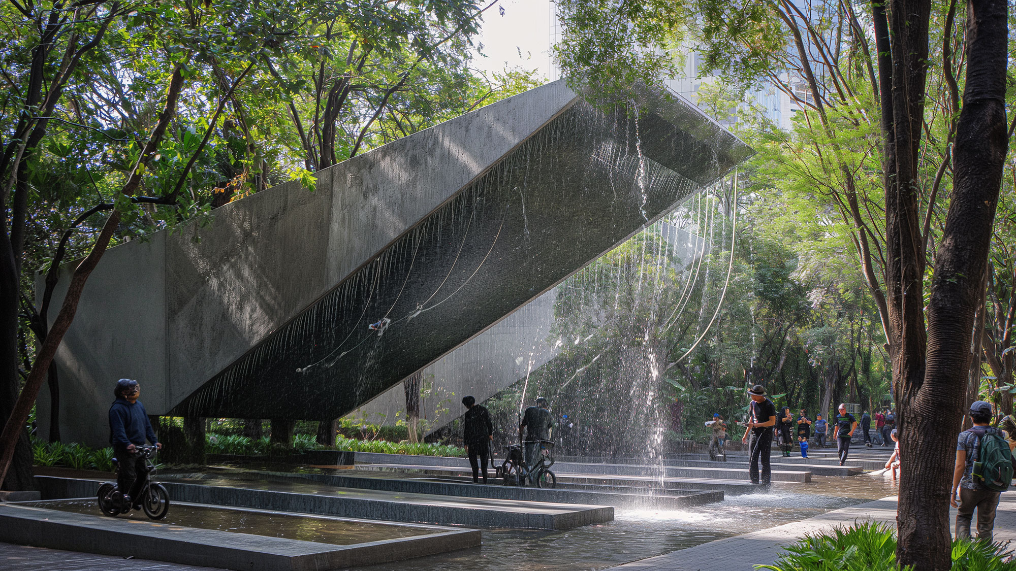 A large water fountain with people walking around.