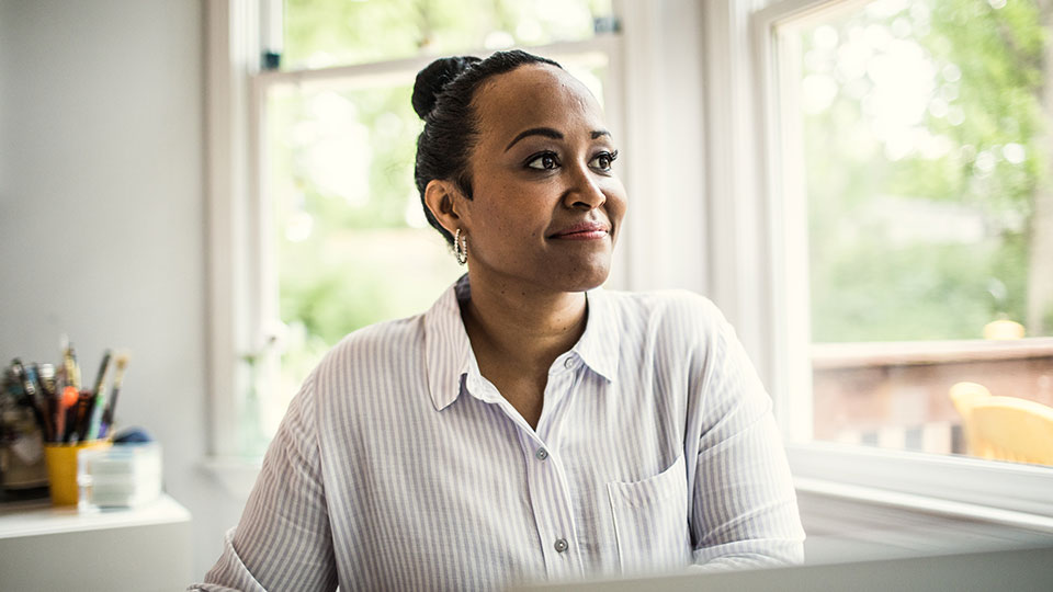 A smiling woman sits in an office environment