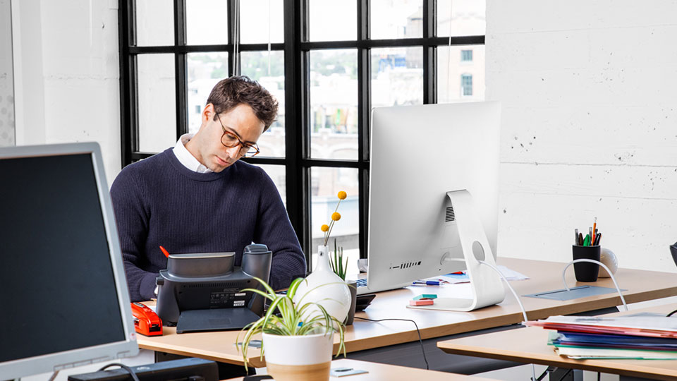 A man sits at a workspace focused on writing