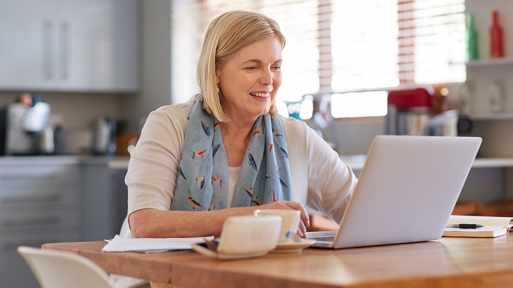 billede af kvinde ved køkkenbordet, der kigger på mail på en computer