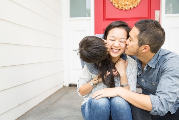 A family hugging on their front porch