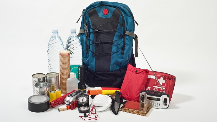 Photo of a backpack, first aid kit, radio, water, and other emergency supplies.