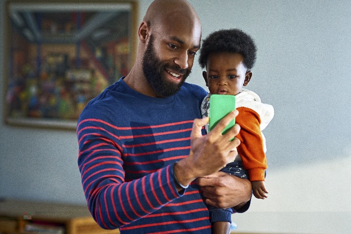 Photo of a man holding a small child and talking on the phone