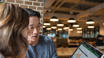 Pareja en una cafetería mirando un gráfico de Excel