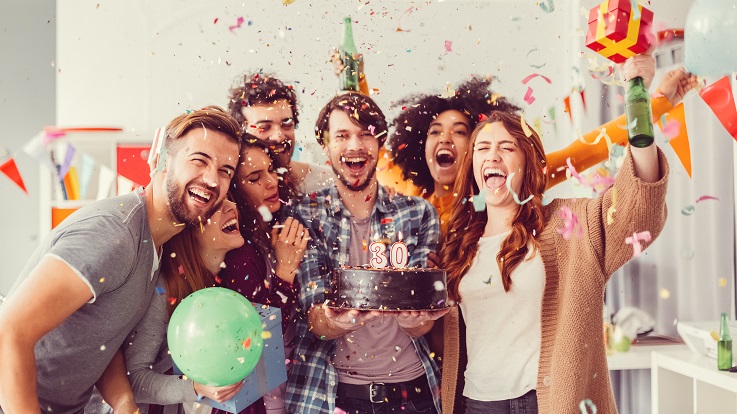 Photo d’un groupe d’amis célébrant avec de la nourriture, des boissons et des confettis.