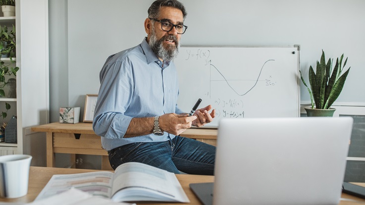 Foto de um professor em um quadro com um laptop.