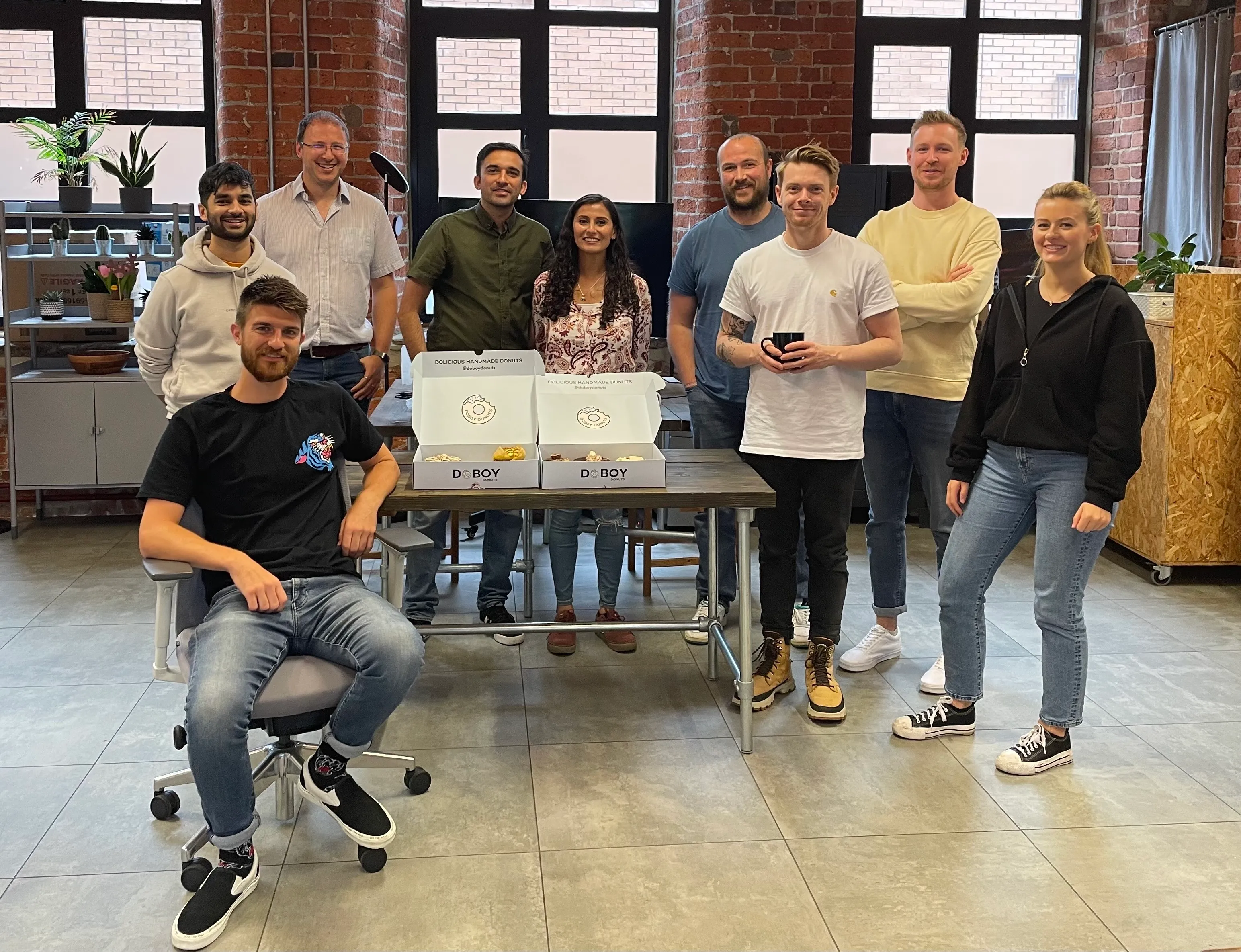 Synap team gathered round a desk with donuts